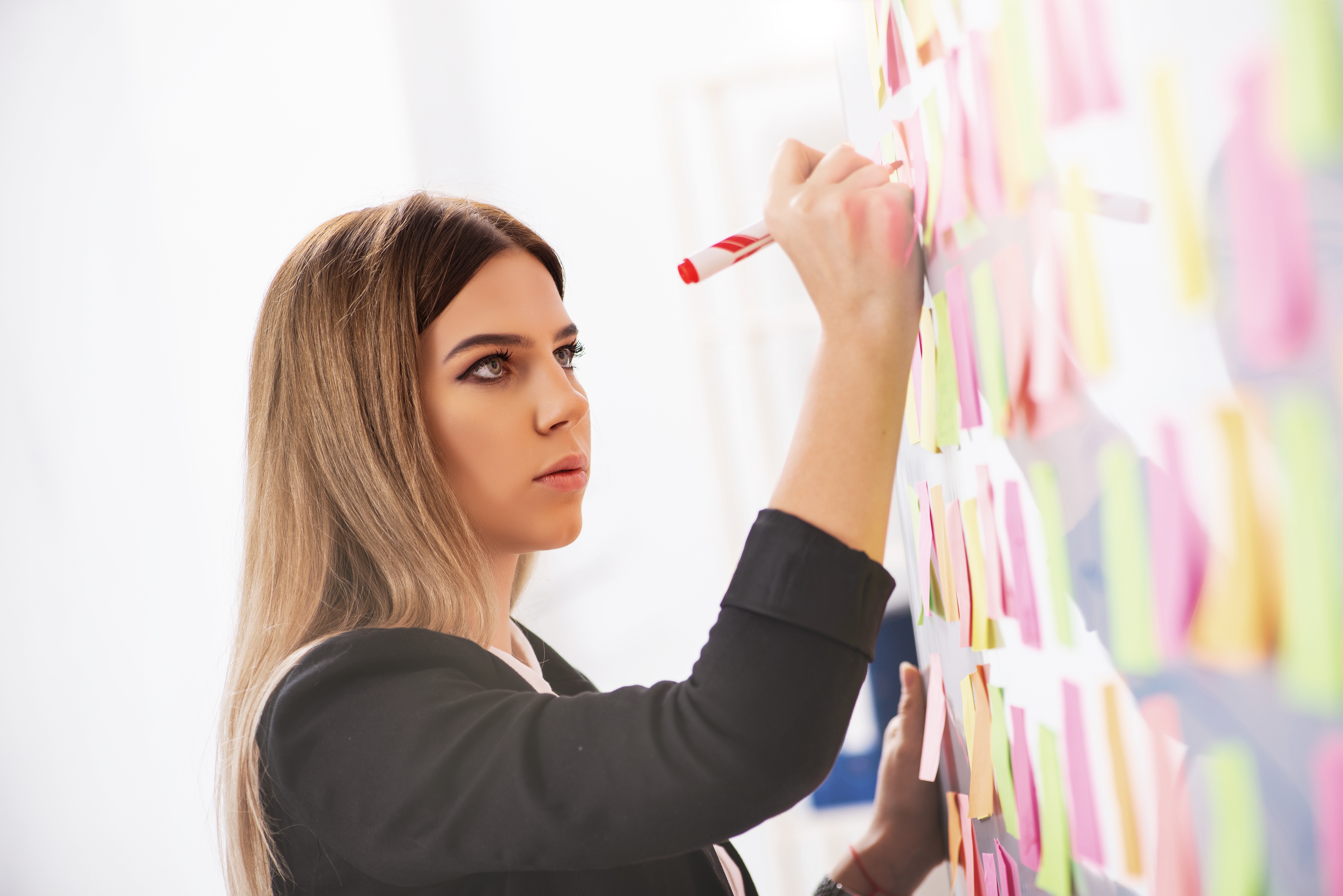 Eine Frau schreibt auf Post Its an der Wand