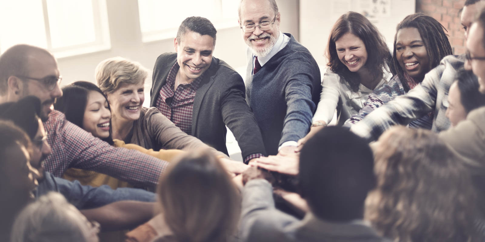 Ein Gruppe von Menschen steht im Kreis und motiviert sich selbst