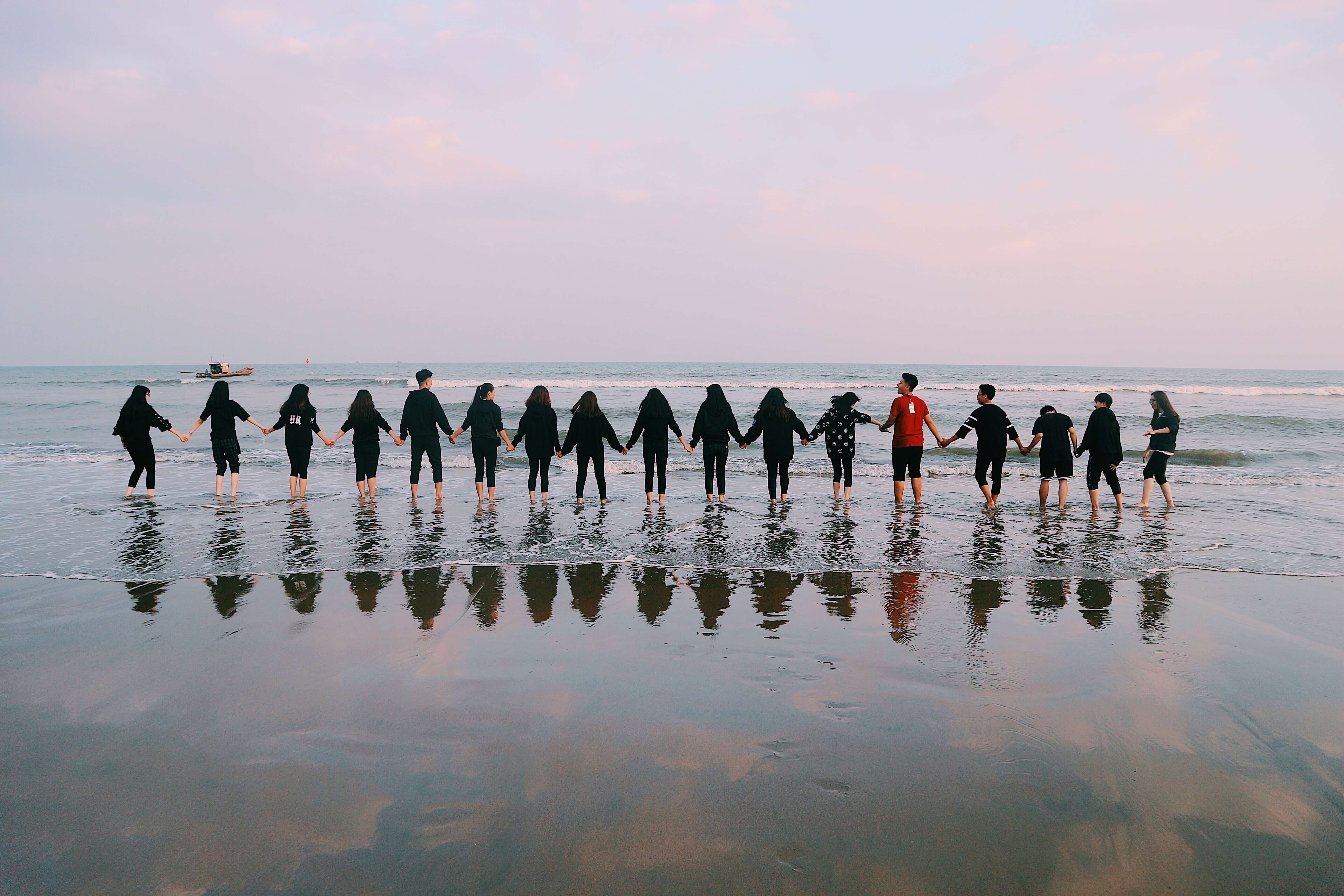 Team hält die Hände am Strand direkt am Wasser