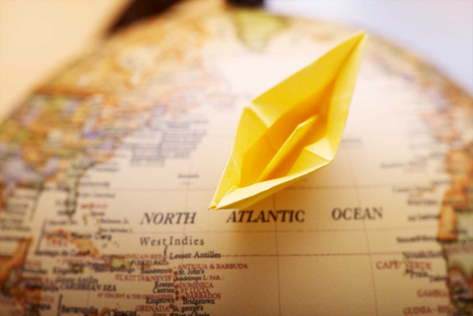 A paper boat crosses the ocean of a globe